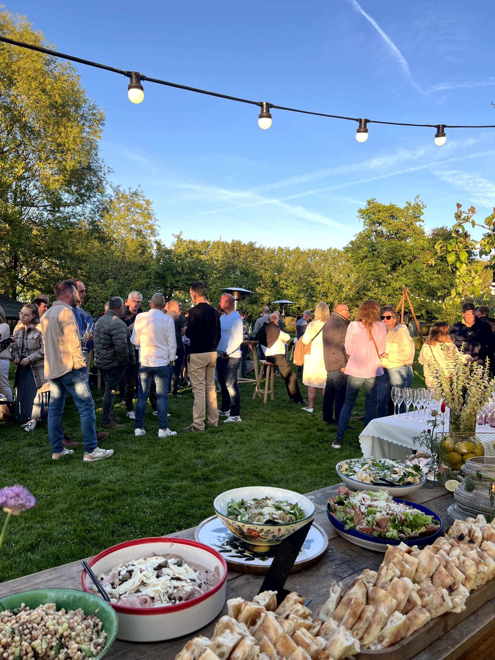 Gasten genieten van receptie en het buffet in de tuin, bedankingsfeest golden crew Rijvers Festival — VeVents